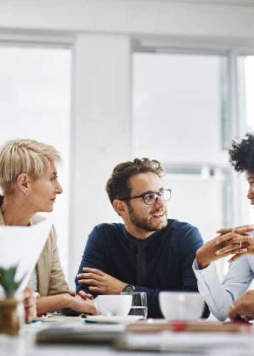 Cropped shot of a diverse group of businesspeople sitting together and having a meeting in the office